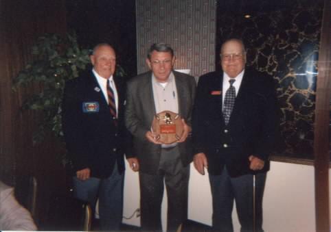 Retired Camanche Fire Chief Bill Rowe proudly displays Roger Mooty award with President Charles M. Conklin and Board member Dick Grimm at the 2002 Fall Conference in Algona.